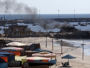 Smoke billows from a beach shack following an Israeli military strike, on July 16, 2014 in Gaza City which killed four children, medics said. All four were on the beach when the attack took place, emergency services spokesman Ashraf al-Qudra said, with several injured children taking refuge at a nearby hotel where journalists were staying. AFP PHOTO / THOMAS COEX