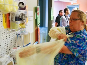 RN Lorna Kellow, left, dons personal protective equipment outside an isolation room in B3 on Wednesday, July 16, 2014 next to hospital staff and medical officer of health Dr. Rosana Pellizzari at Peterborough Regional Health Centre.  Dr. Jamie Brown, the physician in charge of infection prevention and control at the hospital, said nobody died of C. difficile acquired at PRHC during the outbreak. Clifford Skarstedt/Peterborough Examiner/QMI Agency