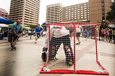 Players attack the net during the Five Hole for Food ball hockey tournament at Centennial Plaza in Edmonton, Alta., on Wednesday, July 16, 2014. The aim of the tournament is to gather donations for local food banks. Edmonton is the 11th stop out of 13 on this year's tour. Codie McLachlan/Edmonton Sun/QMI Agency