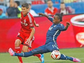 Vancouver’s Darren Mattocks slides to try to take the ball from TFC defender Mark Bloom during Wednesday night’s game. (CRAIG ROBERTSON/Toronto Sun)