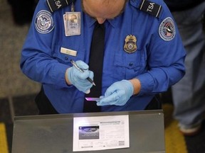 A Transportation Security Administration (TSA) agent uses a special light to check the authenticity of a traveller's driver's license at Ronald Reagan Washington National Airport in Washington November 24, 2010. Reuters/Jason Reed