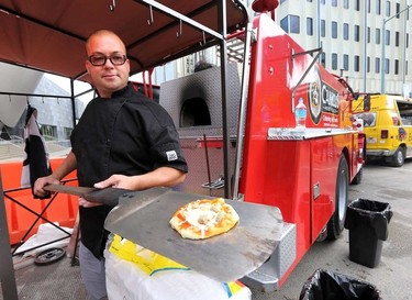 Jason Paquette with Canicus Wood Fired Pizza shows off one of his pies from a wood buring oven built in a converted fire truck during the opening day for Taste of Edmonton at Churchill Square in Edmonton, Alberta on July 17, 2014.  Perry Mah/Edmonton Sun/QMI Agency