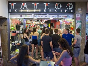 Young British tourists line up outside a tattoo shop of Punta Ballena street in the Magalluf zone, in Calvia on Mallorca Island late on July 18, 2014.   AFP PHOTO/ JAIME REINA