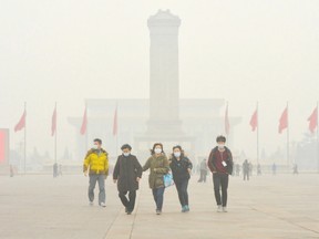 Chinese tourists wear face masks during a visit to Tiananmen Square in February as heavy air pollution shrouded Beijing. A letter writer says British Columbia has a carbon tax that recycles the revenue back to households and per capita fossil fuel use has decreased. (AFP FILE Photo)