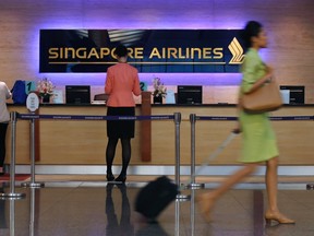 People walk past a Singapore Airlines ticketing counter at Changi Airport in Singapore May 7, 2014. REUTERS/Edgar Su