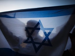 An Israeli holds a flag during a protest in Jerusalem, in support of Israel's offensive in the Gaza Strip, July 14, 2014.

REUTERS/Ronen Zvulun