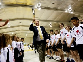 Dr . Andrew Pipe, President of Commonwealth Games Canada carries a torch through children. Photo Supplied