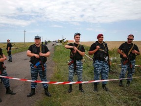 Armed pro-Russian separatists stand guard at a crash site of Malaysia Airlines Flight MH17, near the village of Hrabove, Donetsk region July 20, 2014. Ukraine on Sunday accused separatist rebels of hiding evidence that a Russian missile was used to shoot down the Malaysian airliner, while Britain said Moscow faced "pariah" status and the threat of further economic sanctions. REUTERS/Maxim Zmeyev