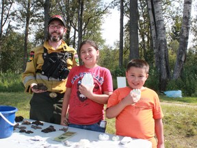 Makayla Wolftail,  and Everett Wolftail, , pose with Alberta Environment and Sustainable Resource Development (ESRD) firefighter Victor Cernik in front of the ESRD display of wildlife signs during last year's Family Fun Day.
File photo | Whitecourt Star