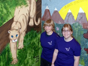 Lauren Fisher and Amanda Frost stand beside their painting of a stalking cougar in the Calgary Tower. The duo's work is featured on landing 41-A of the iconic building and was painted as part of the Alberta Wilderness Association's Climb and Run for Wilderness mural competition. Photo submitted by Darcy Fisher.