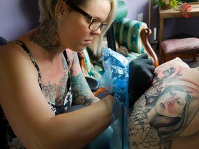 Aimee Allen fills in the tattoo of St. Michael on the back of Candace Amoun at Taste of Ink on Wellington Street in London. (Mike Hensen/The London Free Press/QMI Agency)