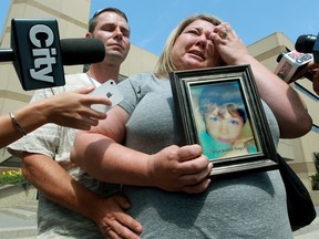 David Pentecost and Crystal Pentecost hold a photo of their son Dawson as they speak to the media while requesting the public's help in returning a necklace that was recently stolen, outside EPS headquarters in on Tuesday . The necklace holds the remains of their son Dawson, 9, who was killed in a February 10, 2013 plane crash. (DAVID BLOOM/EDMONTON SUN)