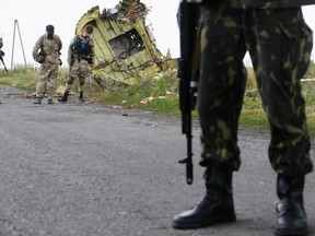 An armed pro-Russian separatist stands guard as monitors from the Organization for Security and Cooperation in Europe (OSCE) and members of a Malaysian air crash investigations team inspect the crash site of Malaysia Airlines Flight MH17 near the village of Hrabove (Grabovo), Donetsk region July 22, 2014. Almost 300 people were killed when the Malaysian airliner went down last Thursday. (REUTERS/Maxim Zmeyev)