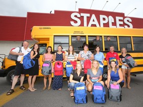 Madison Ellis, fifth from left, is flanked by volunteers, representatives from local radio stations and Cindy Martindale of Staples in Belleville, Ont., third from left in back row, are ready to stuff a mid-size school bus with more than 75 backpacks supplied by Quinte Mall retailers as they launch the 14th edition of United Way of Quinte's Good Backpack Program Wednesday morning, July 23, 2014. - Jerome Lessard/The Intelligencer/QMI Agency