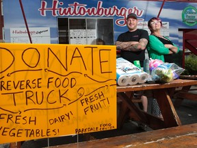 Thomas Williams, owner of the Hintonburger and Karen Secord, executive director of the Parkdale Food Centre, stand in front of the reverse food truck in Ottawa Wednesday July 23,  2014. Tony Caldwell/Ottawa Sun/QMI Agency