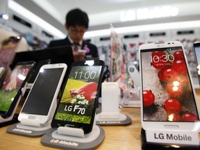 A sales assistant uses his mobile phone in front of mock LG Electronics smartphones displayed at a store in Seoul July 22, 2014. REUTERS/Kim Hong-Ji
