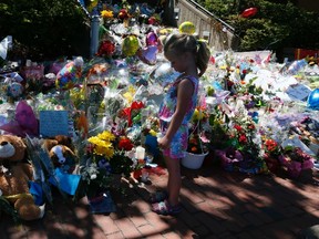 Five-year-old Rachel Ricketts looks at a memorial on the steps of the Royal Canadian Mounted Police (RCMP) headquarters in Moncton, New Brunswick June 11, 2014. REUTERS/Christinne Muschi