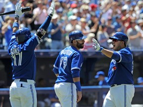 Toronto Blue Jays catcher Dioner Navarro (right) is greeted at home plate by right fielder Jose Bautista and second baseman Ryan Goins after scoring on a two-run single by first baseman Juan Francisco in the fourth inning at Rogers Centre on July 24, 2014. (DAN HAMILTON/USA TODAY Sports)