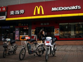 A woman walks past electric bikes sitting outside a McDonald's fast-food outlet in central Beijing March 20, 2012. (REUTERS/David Gray)