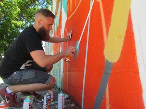 Thunder Bay artist boy Roland finishes off a mural on the wall of the Outdoorsman shop on Mitton Street in Sarnia. He led a Random Acts of Art student workshop for the Judith and Norman Alix Art Gallery this week. (PAUL MORDEN, The Observer)