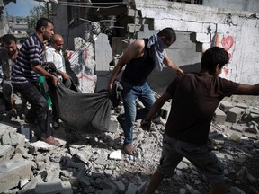 Palestinians carry a body from a destroyed building in Beit Hanoun town, which witnesses said was heavily hit by Israeli shelling and air strikes during an Israeli offensive, in the northern Gaza Strip July 26, 2014. A 12-hour humanitarian truce went into effect on Saturday. REUTERS/Finbarr O'Reilly