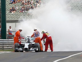 Firefighters try to extinguish the fire on the car of Mercedes driver Lewis Hamilton during the qualifying session of the Hungarian Grand Prix at the Hungaroring circuit, near Budapest on Saturday, July 26, 2014. (Darko Bandic/Reuters/Pool)