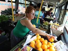 Morrison Gardens resident Susan Lowery picks the fruits and vegetables she wants from an OC Transpo bus full of produce,​ dubbed the MarketMobile — a new pilot project by the city to bring discount, healthy food to the doorsteps of neighbourhoods with limited access to grocery stores and/or limited means to afford healthy food. The food truck rolled out Saturday, July 26, 2014. 
Doug Hempstead/Ottawa Sun/QMI Agency