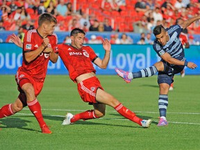 Sporting Kansas City forward Dom Dwyer attempts a shot past Toronto FC defenders during Saturday night’s game. (USA TODAY SPORTS)