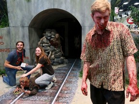 Lyndsay and Don Smith have their photo taken next to a man dressed as a zombie at a booth for "The Walking Dead" during the 2014 Comic-Con International Convention in San Diego, California July 25, 2014.  REUTERS/Sandy Huffaker