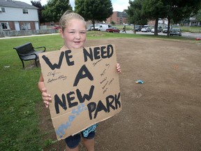 Jay-Lyn Schomberg, 10, made a sign to show her concern that a recently torn-down play structure behind her home will not be replaced. (Ian MacAlpine/The Whig-Standard)