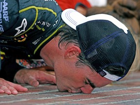 Jeff Gordon, driver of the No. 24 Axalta Chevrolet, celebrates by kissing the bricks after winning the NASCAR Sprint Cup Series Crown Royal Presents The John Wayne Walding 400 at the Brickyard Indianapolis Motor Speedway on Saturday. (AFP)