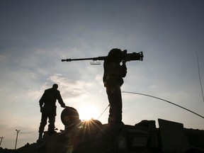 An Israeli soldier holds a weapon atop an armoured personnel carrier (APC) after crossing back into Israel from Gaza July 28, 2014. Israel eased its assaults in the Gaza Strip and Palestinian rocket fire from the enclave declined sharply on Monday, the military said, with both the United States and United Nations calling for a durable ceasefire. REUTERS/Baz Ratner (ISRAEL - Tags: CIVIL UNREST CONFLICT MILITARY POLITICS TPX IMAGES OF THE DAY)