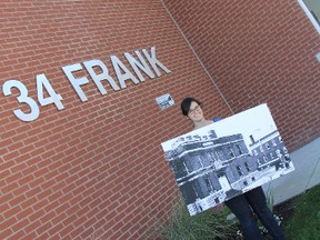This is what 34 Frank St., home of the Strathroy library and museum looked like in 1935. Jordan Brennan, museum exhibits and programming coordinator, takes a break from organizing an exhibit to hold up a photo on July 24 of an armoury (now the spot of the library) where General Sir Arthur Currie had his homecoming. ELENA MAYSTRUK/AGE DISPATCH/QMI AGENCY/