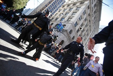 Five-year-old leukemia survivor Miles dressed as "Batkid" and a man dressed as Batman are escorted by police officers back to their Batmobile after they apprehended the "Riddler" as part of a day arranged by the Make-A-Wish Foundation in San Francisco, California November 15, 2013. The young cancer survivor will be treated to various super hero scenarios including receiving a commendation at San Francisco City Hall. REUTERS/Stephen Lam