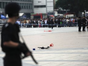 An armed policeman, front, stands guard near a police shield, centre, that was left on the ground after a scuffle between a police officer and an attacker, at a railway station in Guangzhou, Guangdong province in this May 6, 2014 file photo. (REUTERS/Stringer)