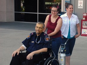 Southwold firefighter Kevin James, left, and his wife Caitlin, centre, look out at dozens of firefighters and a Southwold fire truck gathered outside Victoria Hospital in London on July 12. James died Friday after battling colon cancer and wanted to see and touch the fire truck he was assigned to at least one more time. 
Ben Forrest/Times-Journal