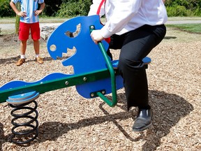 Toronto Mayor Rob Ford on a teeter totter at the opening of a  T-Rex themed playground in Elms Park in Etobicoke on Sunday. (CRAIG ROBERTSON, Toronto Sun)