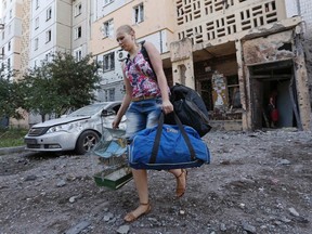 A woman walks out of a damaged multi-storey block of flats carrying her belongings following what locals say was recent shelling by Ukrainian forces in central Donetsk, July 29, 2014. (REUTERS/Sergei Karpukhin)
