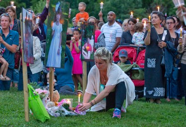 A woman lays a candle beneath a photo of Addison Hall at a candle lit vigil for the six-year-old girl in Greenway Park in London on Wednesday July 30, 2014.  Addison Hall was killed last Friday while walking in a south London Costco store with her mother when the family was struck by a car.
CRAIG GLOVER The London Free Press / QMI AGENCY