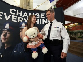 Kaitlyn Mason -Baril pose for photos with Inspector Ed McIsaac (r) at the downtown police headquarters in Edmonton, Alberta on July 30, 2014.  McIsaac had saved Kaitlyn Mason's life 18 years ago and the family wanted to meet and thank him again.  Perry Mah/Edmonton Sun