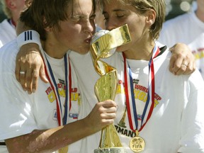 Germany's Maren Meinert (L) kisses the FIFA trophy next to Bettina Wiegmann after defeating Sweden  2-1 at the FIFA 2003 Women's World Cup final in Carson, California, October 12, 2003. Germany's Nia Kuenzer scored the game winning goal in overtime.