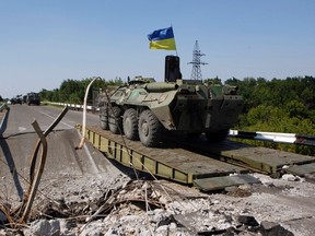 A Ukrainian army APC crosses a destroyed bridge near the eastern Ukrainian settlement of Debaltseve, Donetsk region Aug. 1, 2014. REUTERS/Valentyn Ogirenko