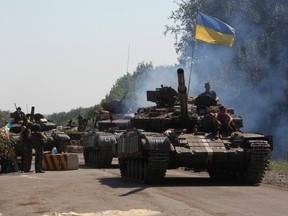 Ukrainian army tanks move past a checkpoint as they patrol the area near eastern Ukrainian town of Debaltseve Aug. 3, 2014. REUTERS/VALENTYN OGIRENKO