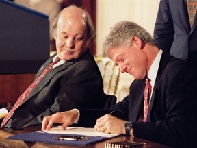 President Bill Clinton, right, signs into law the Brady bill as former White House press secretary James Brady, the bill's namesake, looks on in this file photo from November 30, 1993 at the White House in Washington. (REUTERS/Staff/Files)