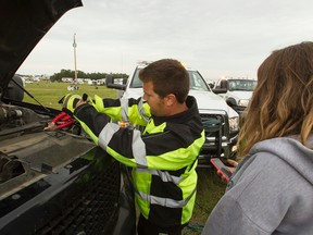 Don Getschel, a tow truck driver subcontracted with Fleetwood Towing and Recoveries, works to boost Brenna Jobe's Ford Expedition at the Big Valley Jamboree 2014 site in Camrose, Alta., on Monday, Aug. 4, 2014. He check the very busy dispatch channel next to his truck. Ian Kucerak/Edmonton Sun/QMI Agency