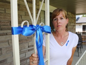 Krista Wells Pearce stands next to a blue ribbon tied on the front step of her west-end house to draw attention to a Kingston man and two of his colleagues embroiled in a sexual abuse investigation in Indonesia 
(Elliot Ferguson/The Whig-Standard)