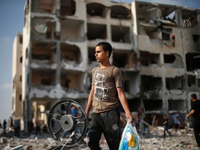 A Palestinian carries his belonging as he walks past a badly damaged residential building after returning to Beit Lahiya town, which witnesses said was heavily hit by Israeli shelling and air strikes during the Israeli offensive, in the northern Gaza Strip August 5, 2014.  REUTERS/Suhaib Salem