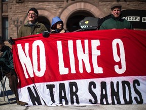People hold a sign during a protest on the National Energy Board's approval to reverse the flow of the Enbridge oil pipeline "Line 9" at Queen's Park in Toronto, March 7, 2014. (REUTERS FILE PHOTO/Mark Blinch)
