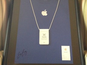 Sam Sung's business card, an Apple T-shirt and a necktag are seen in the frame. Sung, a former Apple employee, is auctioning them off for charity. (eBay/HO)