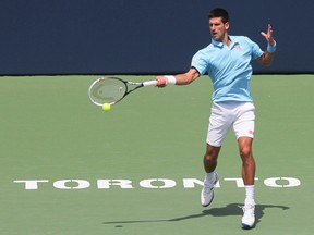 Gael Monfils (FRA)(green/black shirt),  in action against number 1 ranked Novak Djokovic (blue shirt). Stan Behal/Toronto Sun/QMI Agency